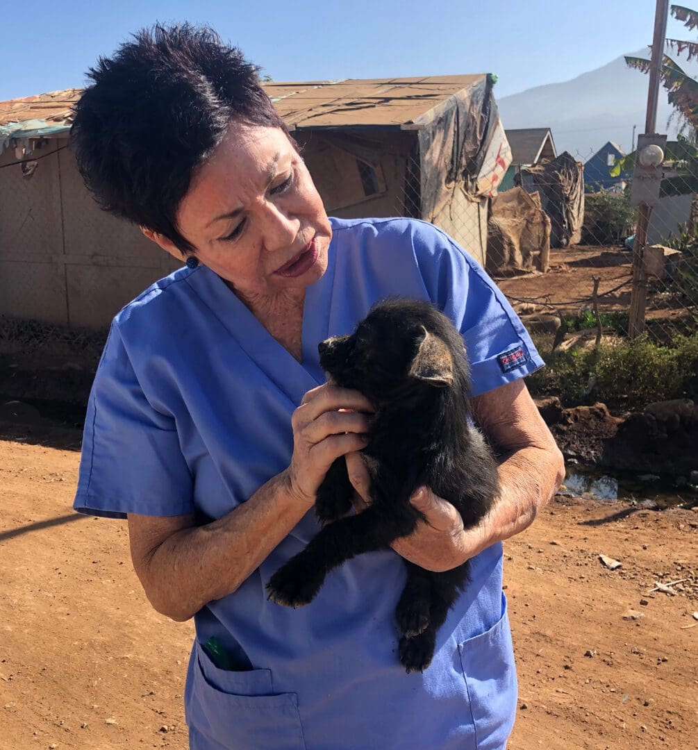 A woman holding a black dog in her arms.