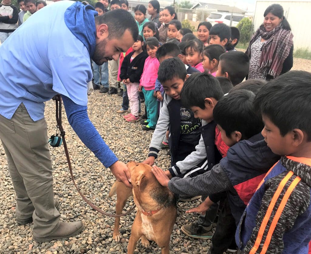 A man is petting a dog while people watch.