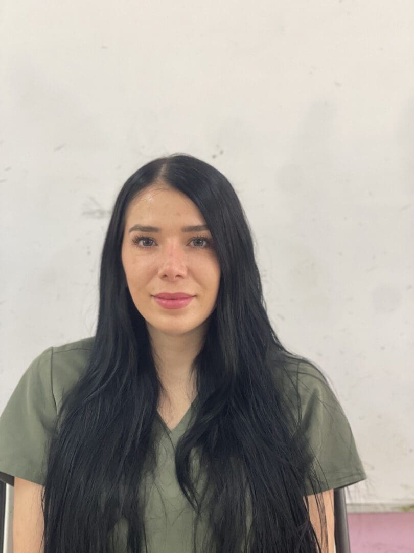 A woman with long black hair wearing green shirt.