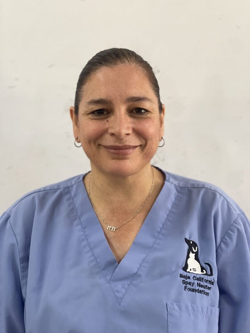 A woman in blue scrubs standing next to a wall.