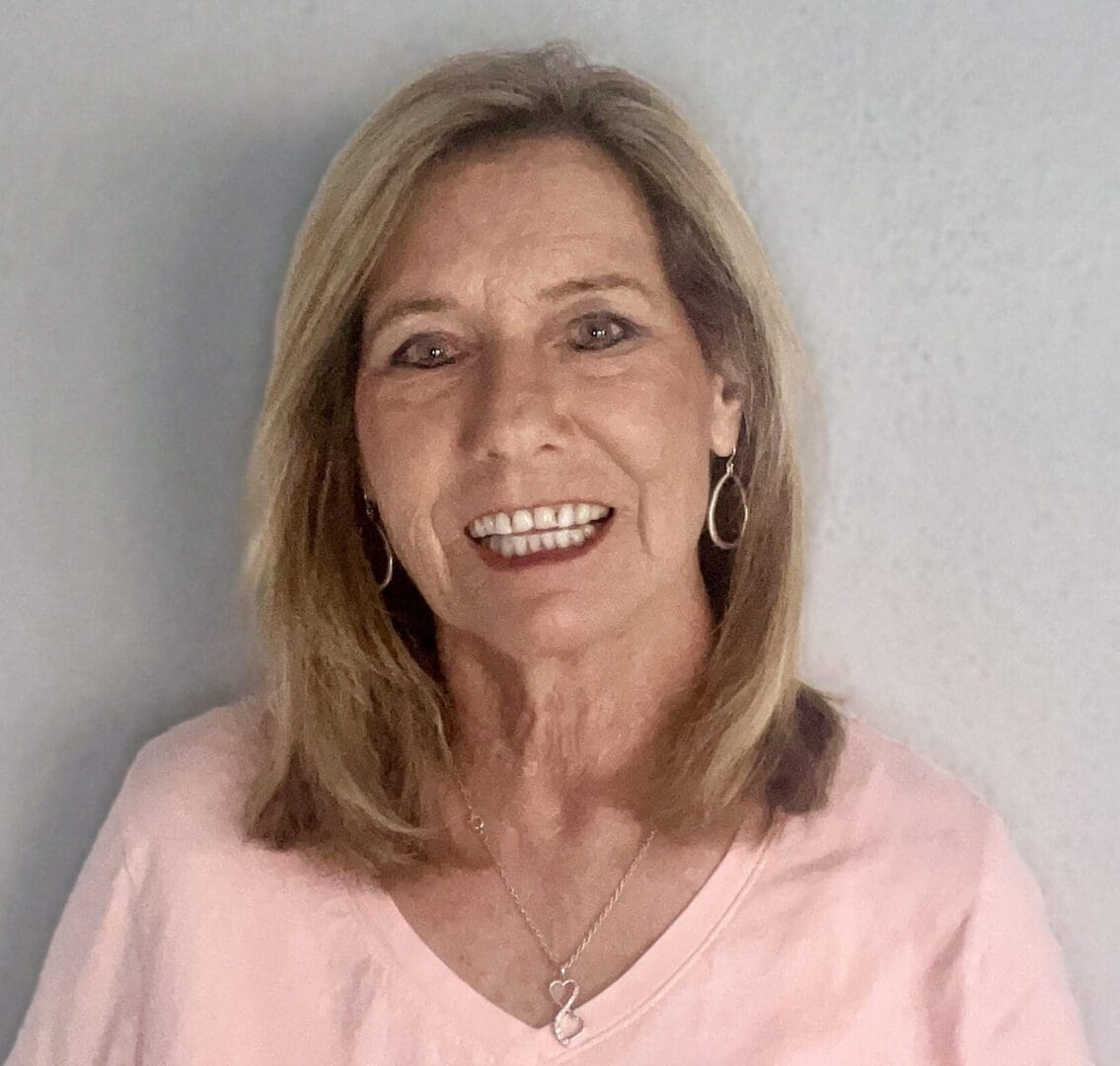 A woman in pink shirt smiling for the camera.